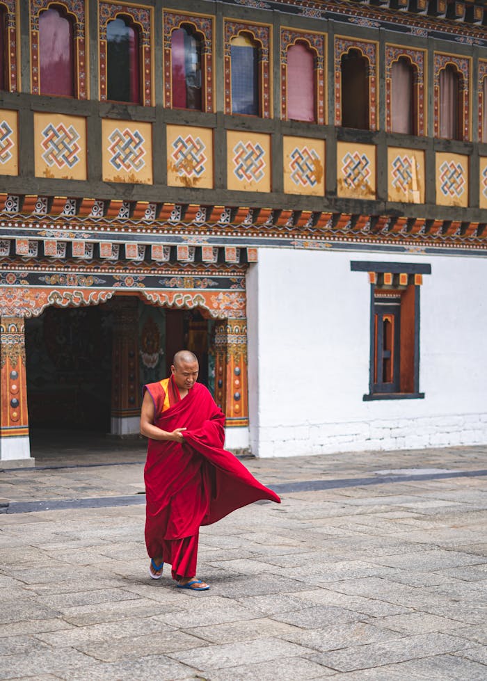 services-01 A monk in traditional attire walks through a beautifully decorated Bhutanese monastery, showcasing cultural and spiritual heritage.